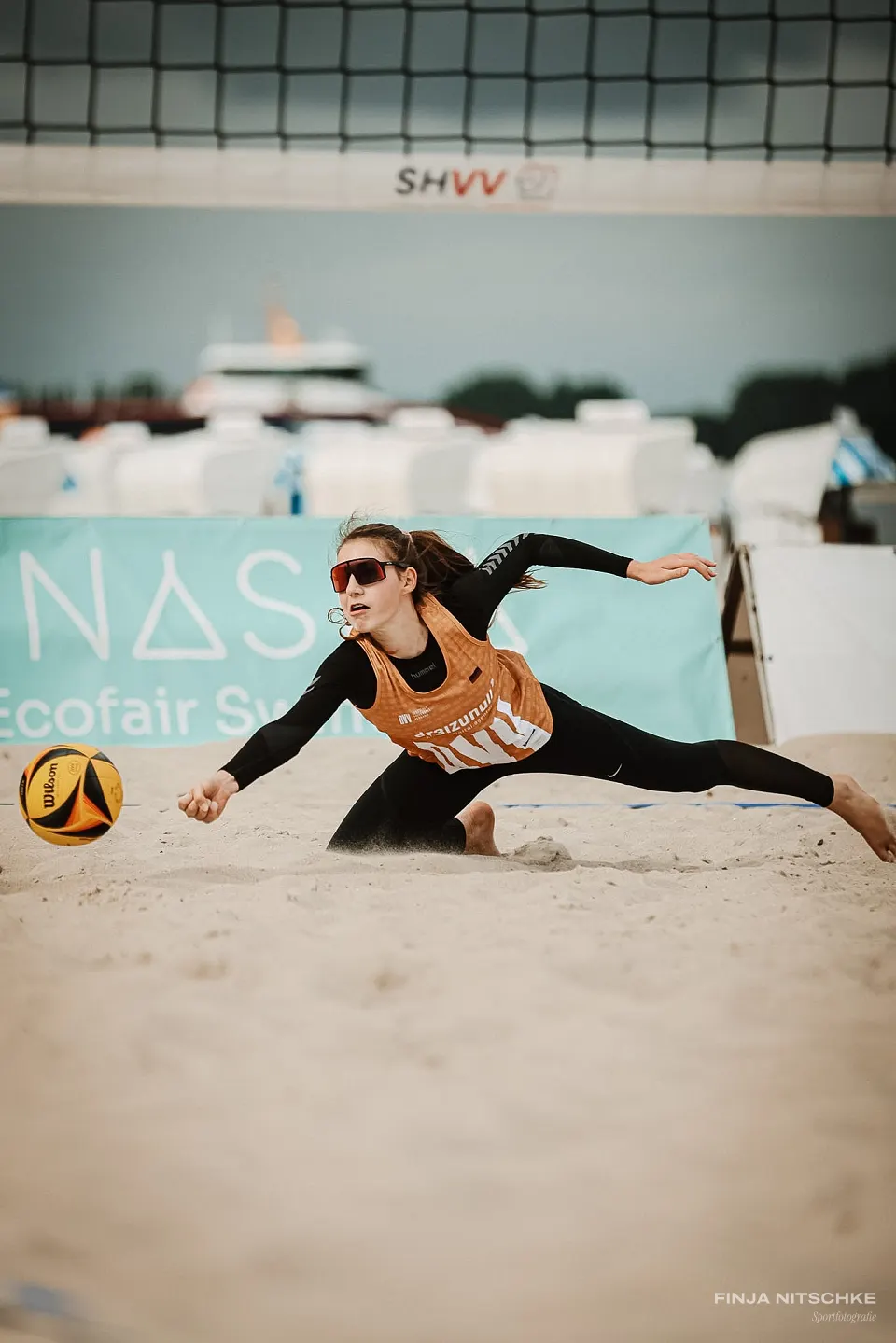 Beachvolleyballerin hechtet mit ausgestrecktem Arm nach dem Ball